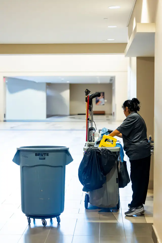 Corporate housekeeping staff with a cleaning cart in an office corridor