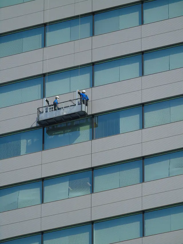 Cleaners on a suspended platform washing the glass facade of an office building
