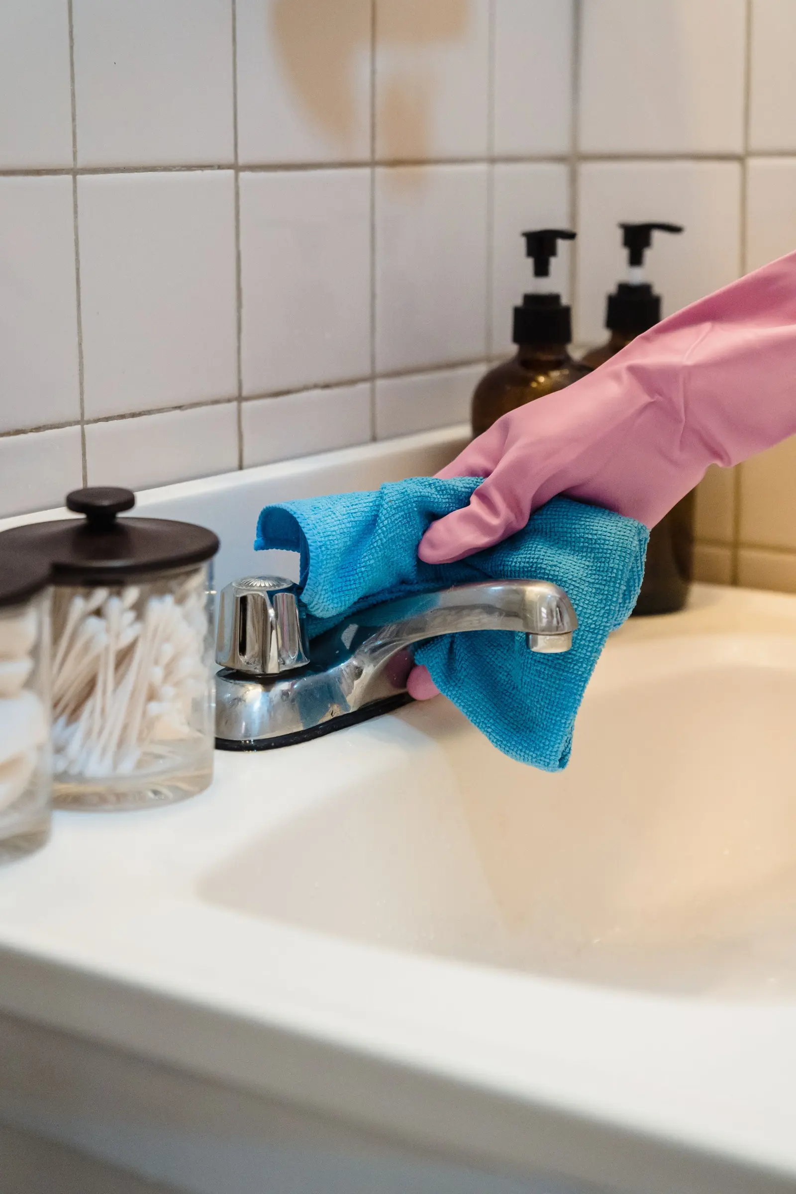Bathroom faucet being disinfected with a cloth during a home sanitization treatment in Delhi NCR