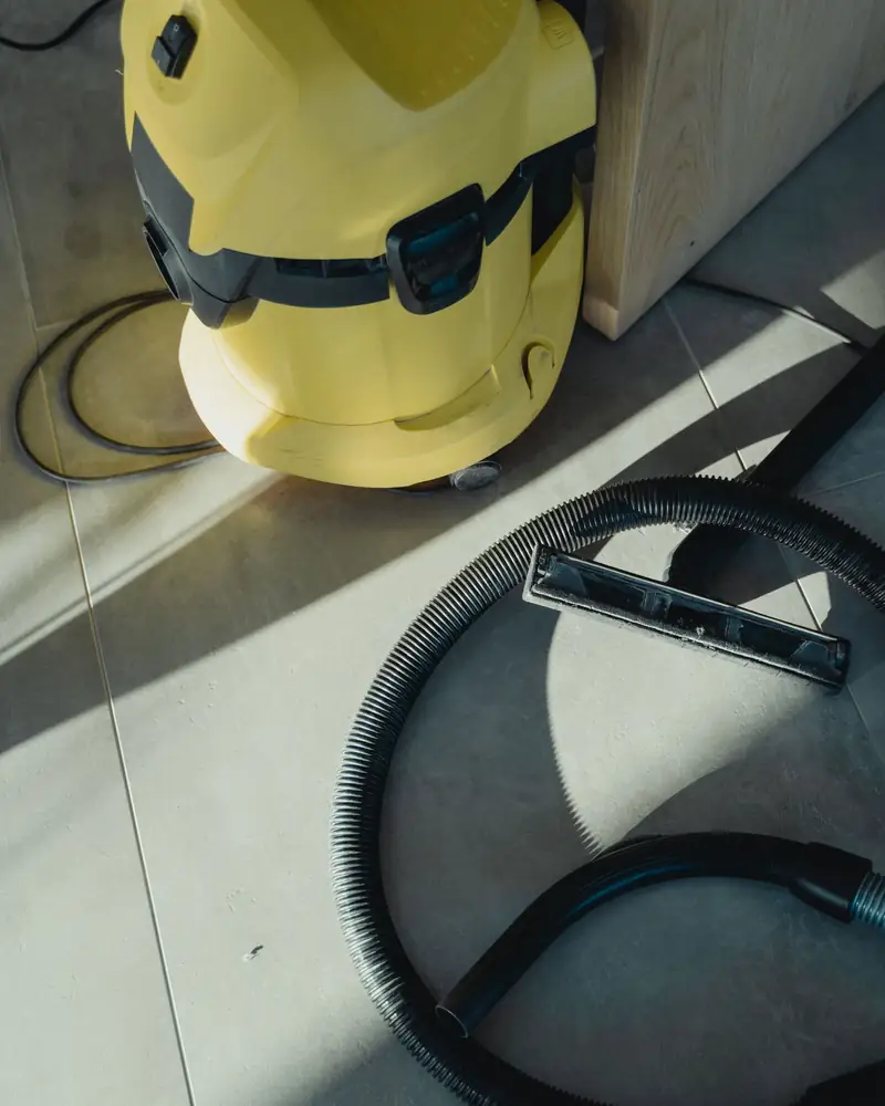 Industrial wet vacuum with extraction hose on a tiled floor