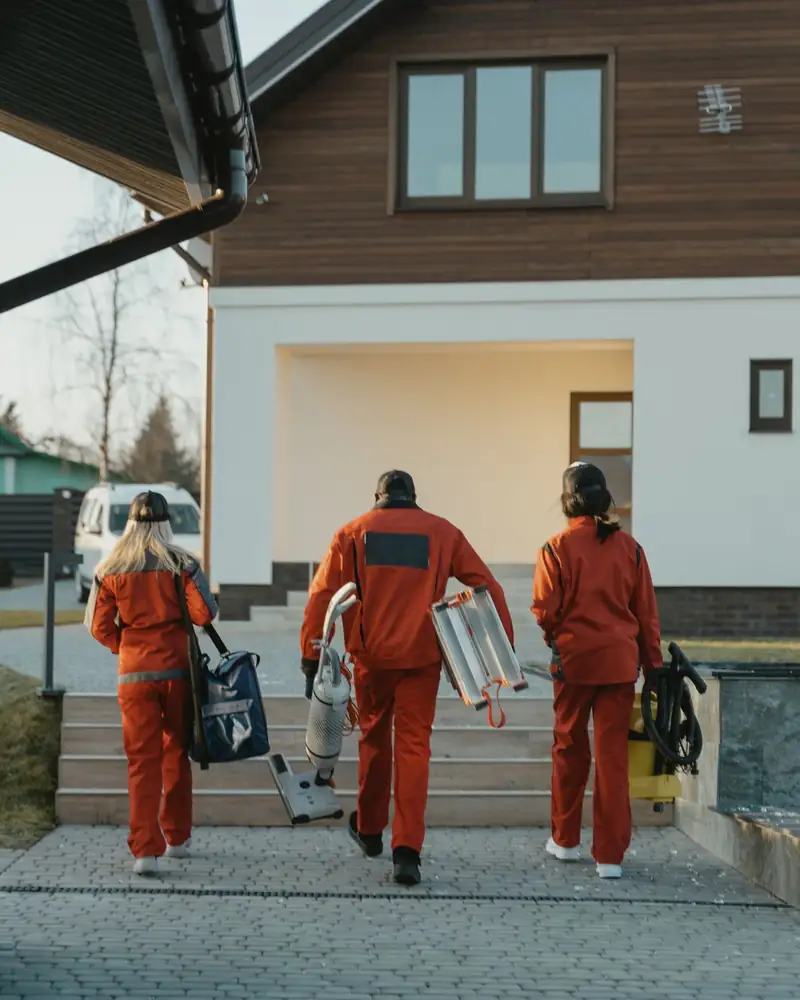 Cleaning team carrying vacuum and equipment arriving at a home for a deep cleaning job