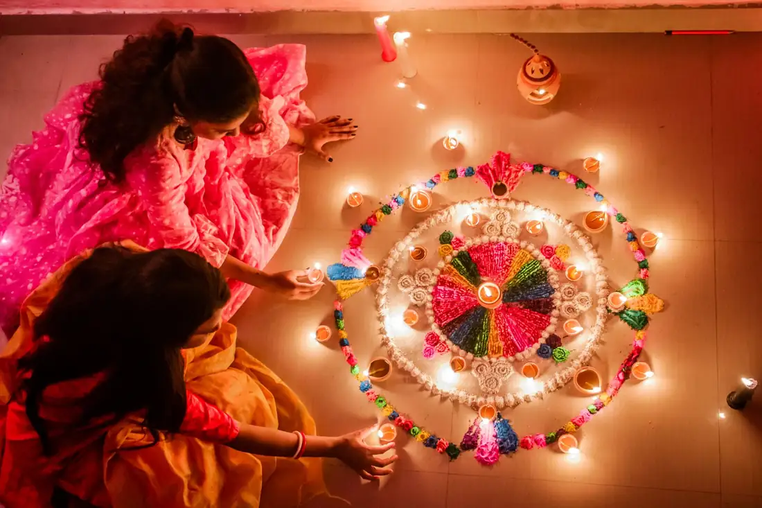 Family lighting diyas around a rangoli at home during Diwali after festive deep cleaning
