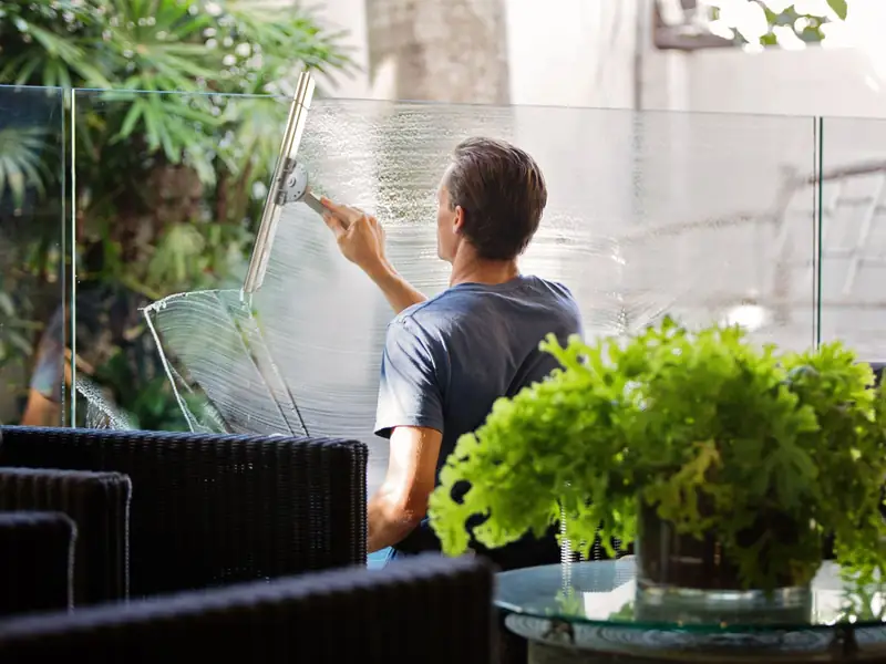 Professional cleaning a large glass panel with a squeegee for a streak-free finish