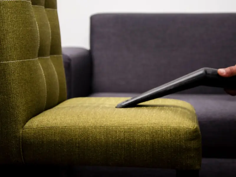 Vacuum nozzle removing dust from a fabric sofa seat cushion