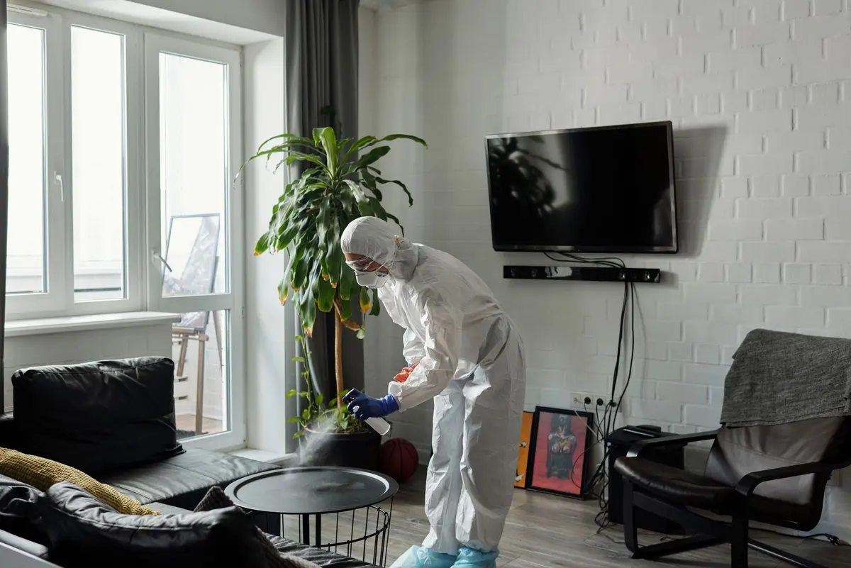 Technician in PPE misting a living room during a professional home sanitization service in Delhi NCR